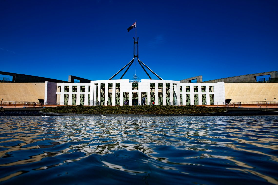 A photograph of Australian federal Parliament with a blue sky behind.
